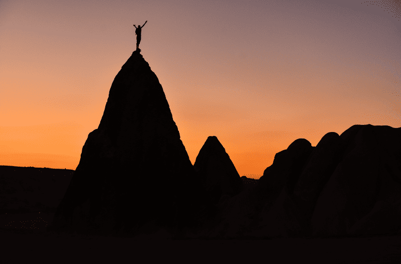 Person standing on a mountain peak at sunset